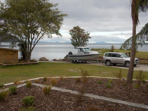 a boat and a car parked next to the water at Braxmere Lodge in Turangi