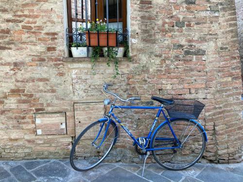 Una bicicleta azul estacionada junto a un edificio de ladrillo en La Casina, en Buonconvento