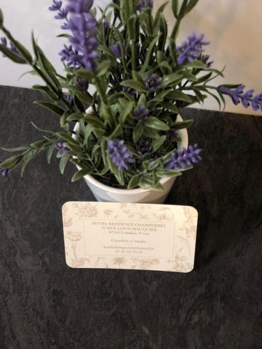 a vase of purple flowers sitting on a table with a plaque at Hôtel Résidence Champerret in Levallois-Perret