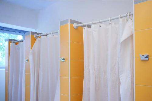 a white shower curtain in a bathroom with yellow walls at Hi! Ostello Milano in Milan