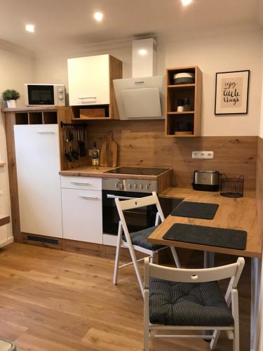 una cocina con electrodomésticos blancos, mesa y sillas en Ferienwohnung Siedlungsnest, en Anklam