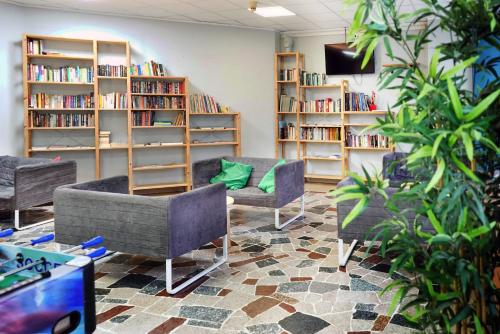 a library with two couches and shelves of books at Hi! Ostello Milano in Milan