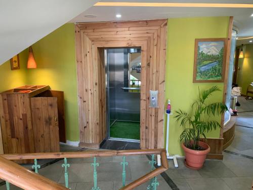 una puerta de madera en una habitación con una planta en D's Casa, en McLeod Ganj