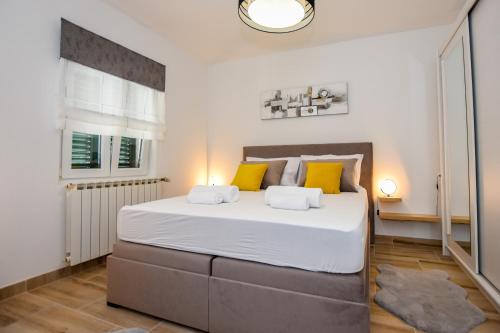 a bedroom with a large white bed with yellow pillows at Apartmani Plazibat in Mandre