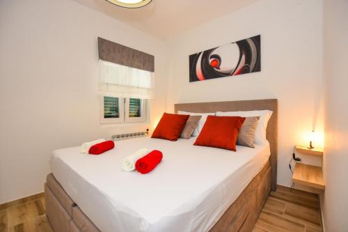 a bedroom with a large white bed with red pillows at Apartmani Plazibat in Mandre