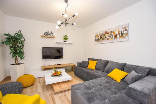 a living room with a gray couch and yellow pillows at Apartmani Plazibat in Mandre