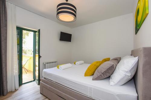 a bedroom with a white bed with yellow pillows at Apartmani Plazibat in Mandre