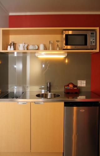 a kitchen with a sink and a microwave at Bentleys Motor Inn in Palmerston North