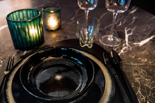 een tafel met een zwarte plaat en wijnglazen bij The 0507 A Luxury Flat in Antwerp in Antwerpen