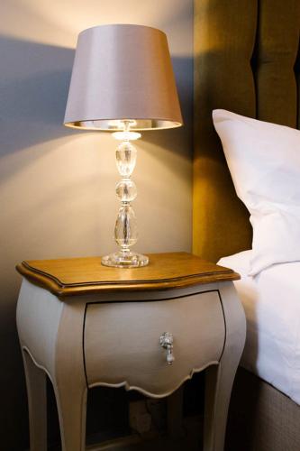 a lamp on a side table next to a bed at Prince of Wales - Townhouse in London