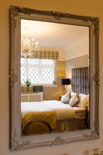 a mirror reflecting a bedroom with a bed and a window at Prince of Wales - Townhouse in London