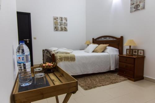 a bedroom with a bed and a table with a bottle of water at Refugio no Campo - AL 1683 in Rapoula do Côa