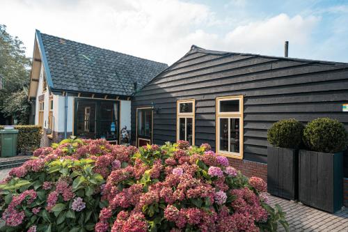 une maison noire avec des fleurs devant elle dans l'établissement Veldzicht, à Winkel