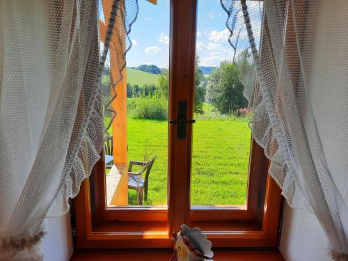 an open window with a view of a green field at Novohradské hory - pronájem na samotě u lesa in Benešov nad Černou