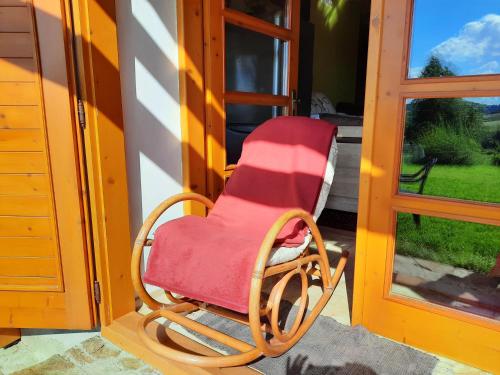 a red rocking chair sitting outside of a door at Novohradské hory - pronájem na samotě u lesa in Benešov nad Černou