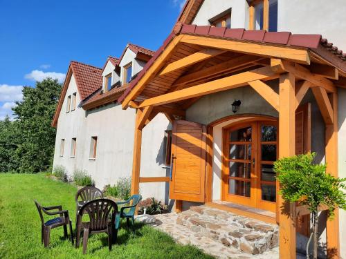 a house with a wooden door and chairs in the yard at Novohradské hory - pronájem na samotě u lesa in Benešov nad Černou
