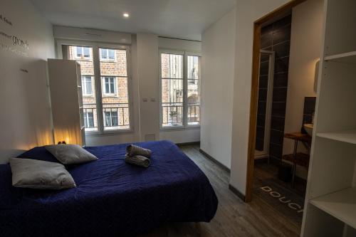 una camera da letto con letto con lenzuola e finestre blu di Grand F2 refait à neuf, Plein coeur Centre Ville a Coutances