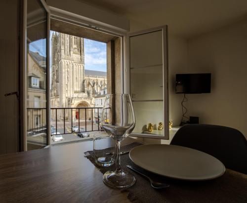 a wine glass sitting on a table with a window at Grand F2 refait à neuf, Plein coeur Centre Ville in Coutances