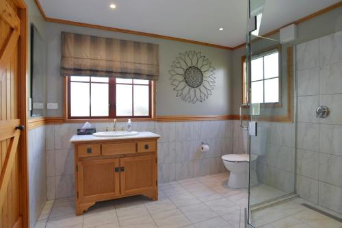 a bathroom with a shower and a sink and a toilet at Terracotta Lodge & Cottages in Carterton