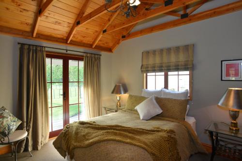 a bedroom with a large bed with a wooden ceiling at Terracotta Lodge & Cottages in Carterton