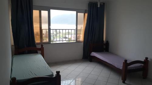 Zimmer mit 2 Betten und einem großen Fenster in der Unterkunft Apartamento frente a praia in Peruíbe