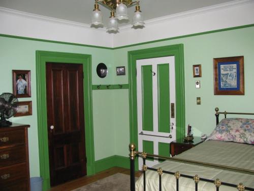 a bedroom with green walls and a bed and a door at Gower Manor Historic Bed & Breakfast in St. John's
