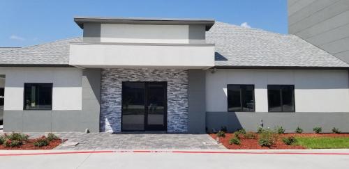 a white house with black windows and a driveway at Studio 6 Deer Park, Tx in Deer Park