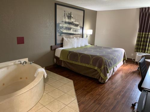 a hotel room with a bed and a bath tub at Super 8 by Wyndham Hernando in Hernando