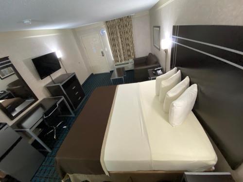 a hotel room with a large bed with white pillows at Deluxe Inn - Fayetteville I-95 in Fayetteville
