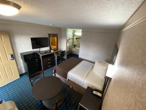 a hotel room with a bed and a television at Deluxe Inn - Fayetteville I-95 in Fayetteville