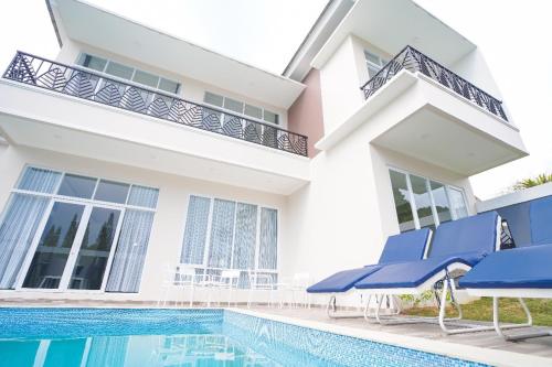 a house with a swimming pool and blue chairs at Marseillia Hills in Puncak