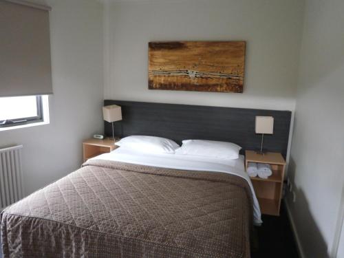 a bedroom with a bed and two night stands with lamps at Sovereign Views Apartments in Ballarat