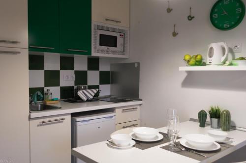 コスタ・テギセにあるEstudio D - Costa Teguiseのキッチン(緑のキャビネット、食器類付きテーブル付)