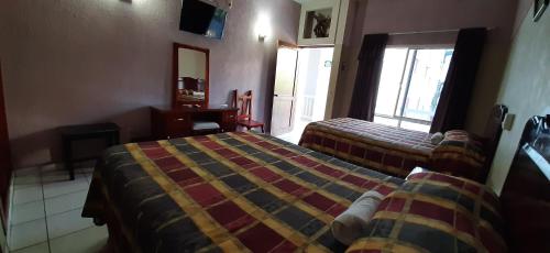 a hotel room with two beds and a window at Hotel San Miguel in Autlán de Navarro