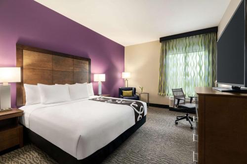 a hotel room with a large bed and a television at La Quinta Inn & Suites by Wyndham Burlington in Burlington