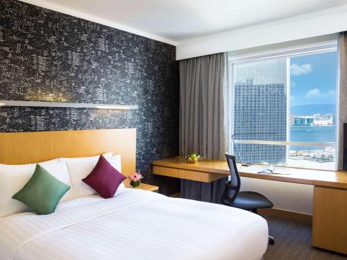 a hotel room with a bed and a desk and a window at Novotel Century Hong Kong in Hong Kong