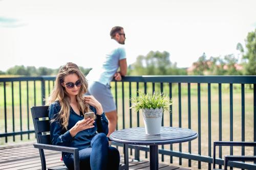a woman sitting at a table looking at her cell phone at Hotel Rondo in Wąbrzeźno