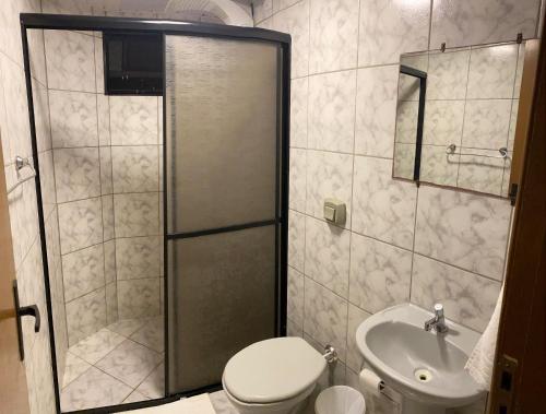 a bathroom with a shower and a toilet and a sink at Pousada Cores in Navegantes