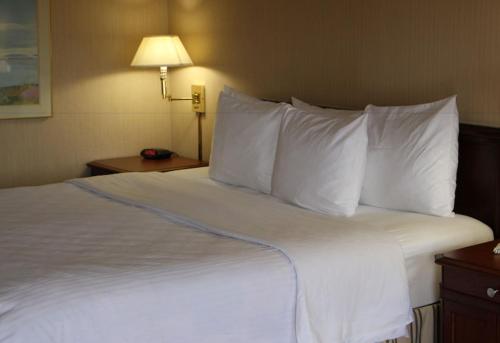a large bed with white pillows in a hotel room at Days Inn & Suites by Wyndham Sunnyvale in Sunnyvale