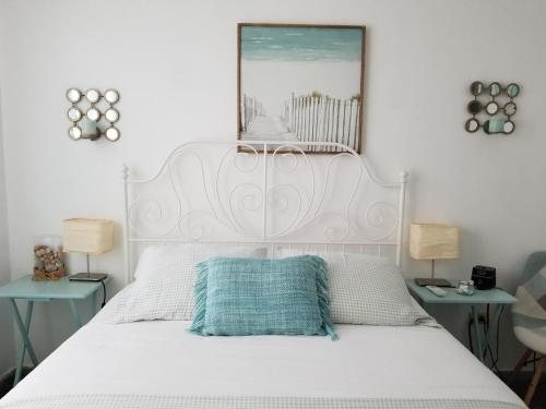 a bedroom with a white bed with a mirror on the wall at Casa Aramana in San Juan