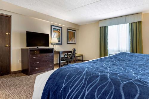 a hotel room with a bed and a desk with a television at Comfort Inn & Suites Butler in Butler