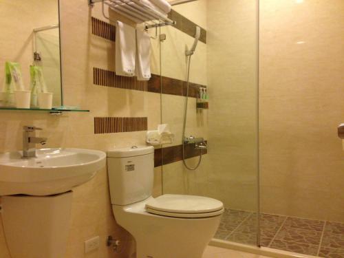 a bathroom with a toilet and a sink and a shower at Doll House Lodge in Hengchun