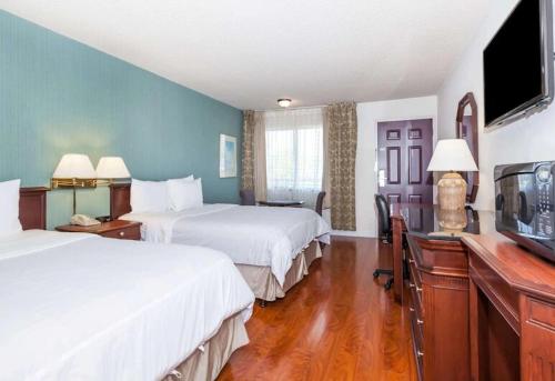 a hotel room with two beds and a flat screen tv at Days Inn & Suites by Wyndham Sunnyvale in Sunnyvale