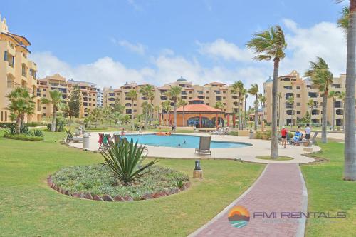 a park with a swimming pool and palm trees and buildings at Princesa C - 402 by FMI Rentals in Puerto Peñasco