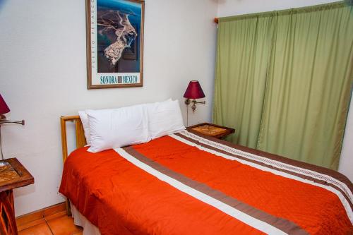 1 dormitorio con 1 cama con manta naranja en La Felicidad, en Puerto Peñasco