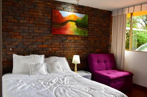 a bedroom with a bed and a purple chair at Casa Iris in Chía