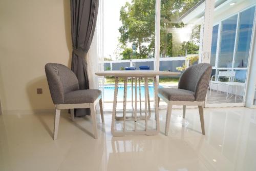 a table and two chairs in a room with a window at Marseillia Hills in Puncak