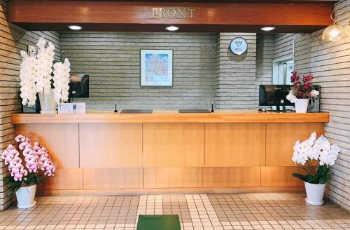 a waiting room with a reception counter and flowers at Hotel All In Well in Hakodate