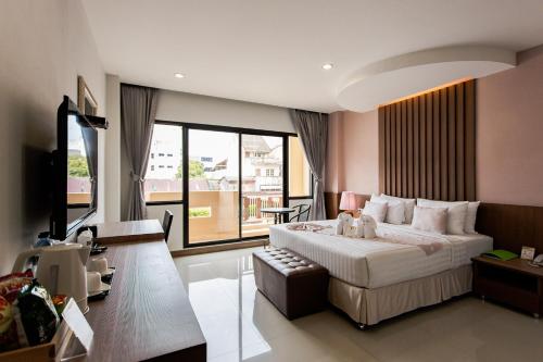 a bedroom with a large bed and a large window at The Centris Hotel Phatthalung in Phatthalung
