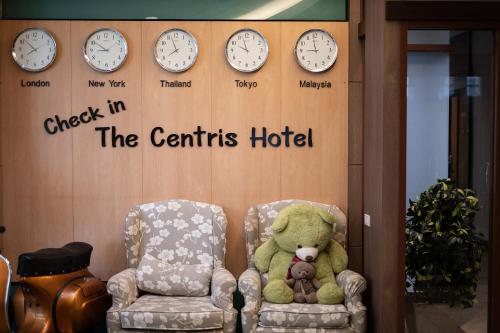 a teddy bear sitting in a chair and clocks at The Centris Hotel Phatthalung in Phatthalung